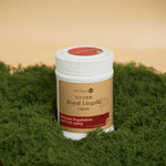Close-up of Royal Lingzhi capsule bottle angled left on moss