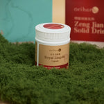 Royal Lingzhi capsule bottle lying on green moss surface angled right